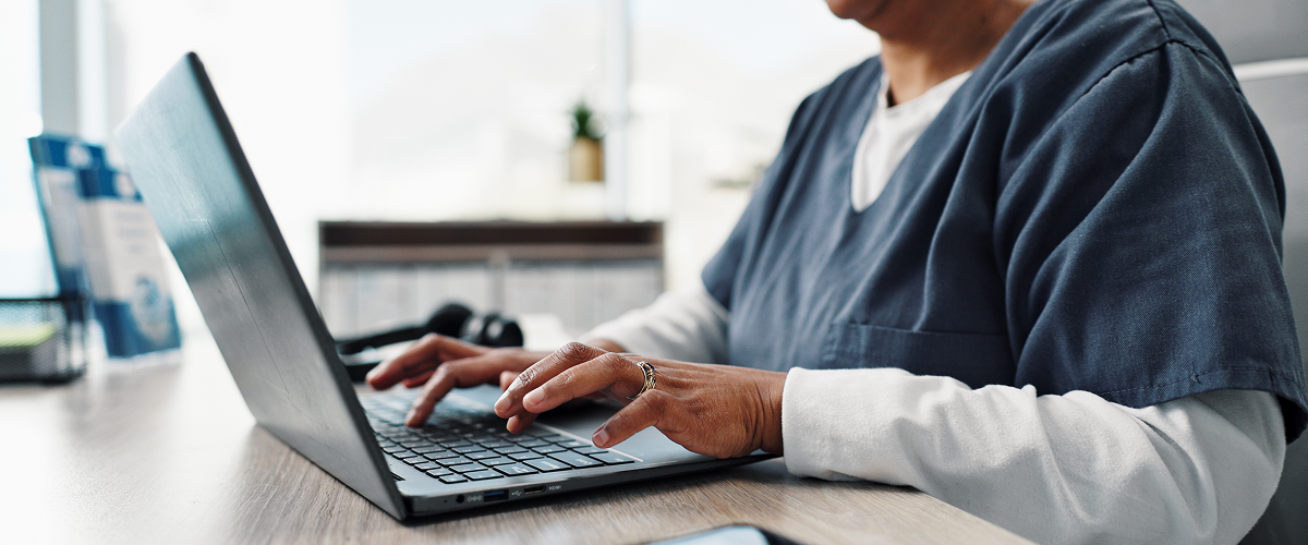Care home manager typing on a laptop while researching how to choose care home software